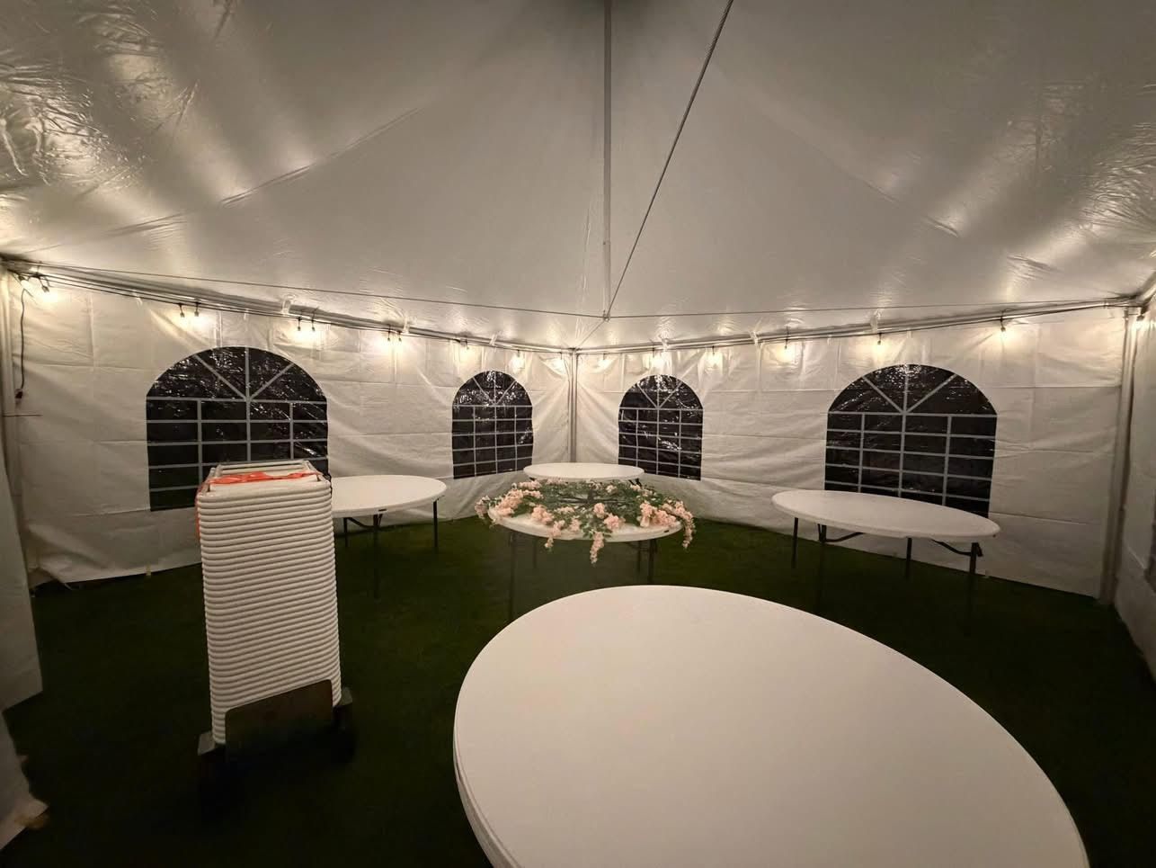 Tables set up inside a white event tent